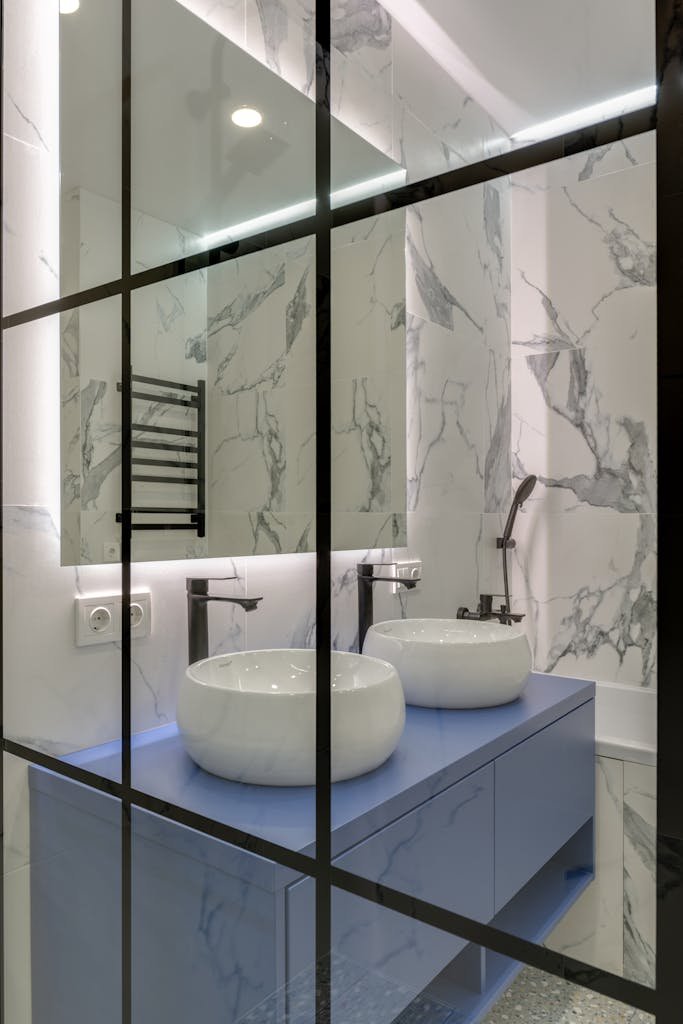 Elegant modern bathroom featuring marble walls, dual sinks, and large mirror.