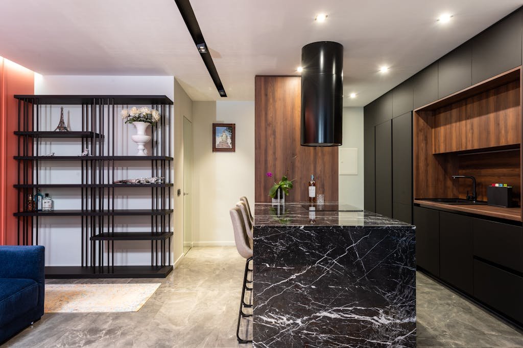 Modern kitchen interior with black marble island and wooden cabinets, featuring a sleek design.